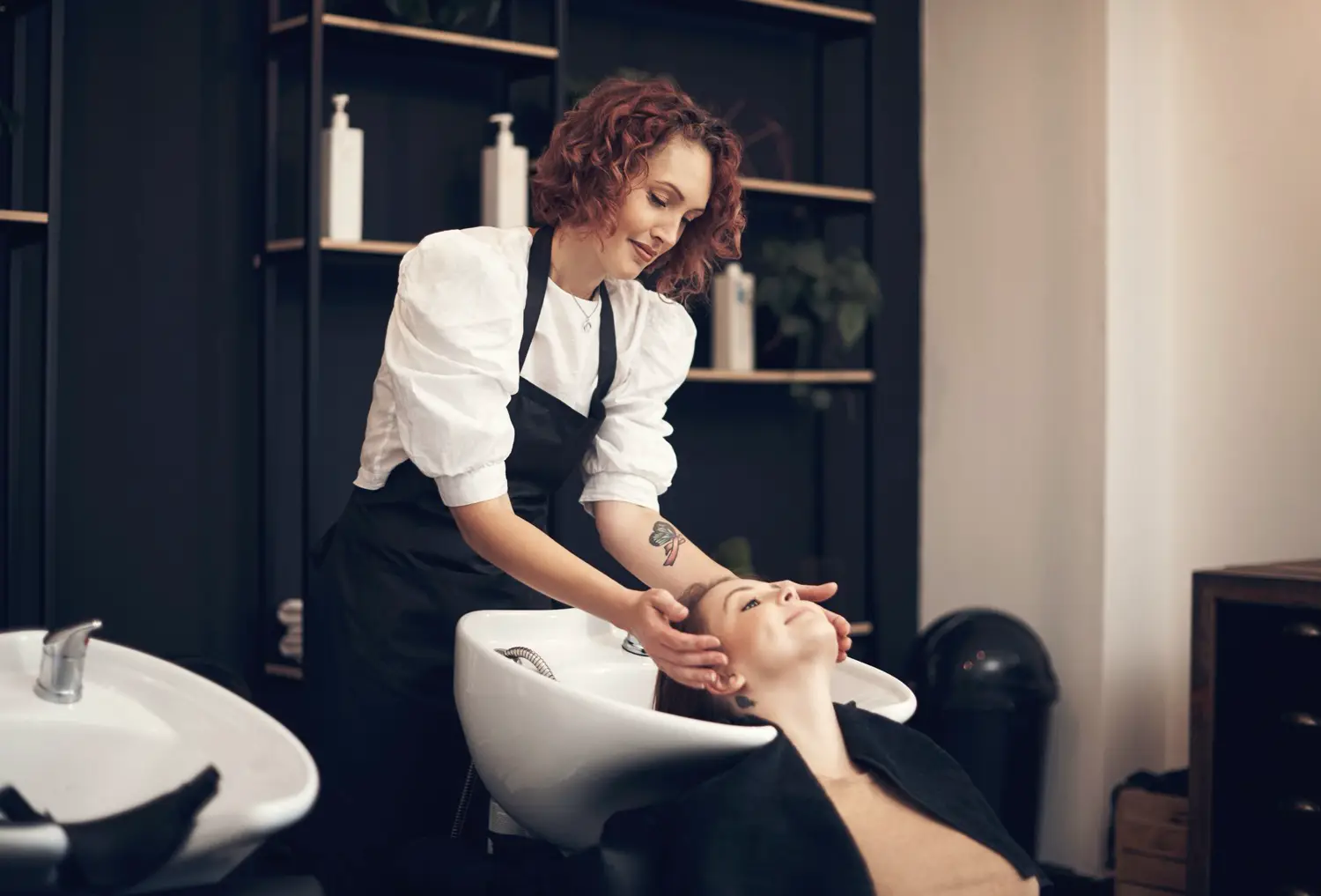 Friseurin bei der Haarwäsche einer Kundin in einem modernen Salon.